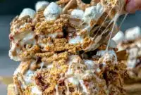 Tray of Golden Grahams S'mores bars with a gooey marshmallow layer, crunchy cereal, and chocolate chips, styled as an easy S'mores Recipe With Golden Grahams.