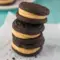 Stack of Homemade Peanut Butter Oreos showing soft chocolate sandwich cookies filled with creamy peanut butter frosting, styled like a rich homemade dessert.