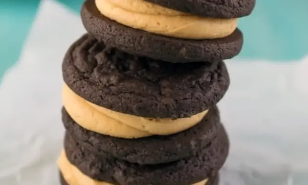 Stack of Homemade Peanut Butter Oreos showing soft chocolate sandwich cookies filled with creamy peanut butter frosting, styled like a rich homemade dessert.