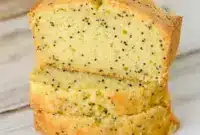 A sliced loaf of Lemon Poppy Seed Zucchini Bread with a soft golden crumb and visible poppy seeds, styled as a fresh Lemon Poppy Seed Dessert for Spring Baking Ideas.