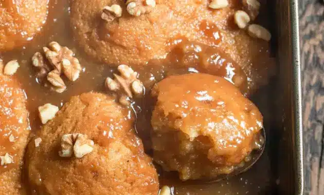 A spoonful of Maple Pudding Cake in a bowl, topped with glossy maple sauce and walnuts — a cozy Maple Syrup Pudding dessert close-up.