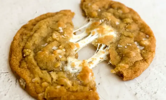 Plate of golden Marshmallow Crispy Cookies: thin, crispy edges with visible Rice Krispies and gooey marshmallow pockets, sprinkled with flaky salt.