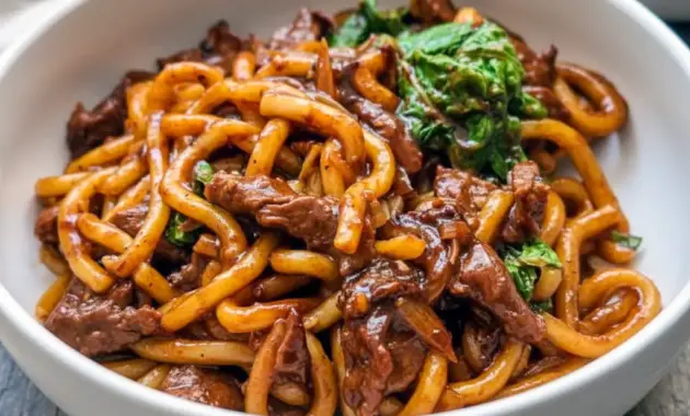 Bowl of Beef Udon with sliced steak, Chinese cabbage, and glossy black-pepper sauce over springy Noodles.