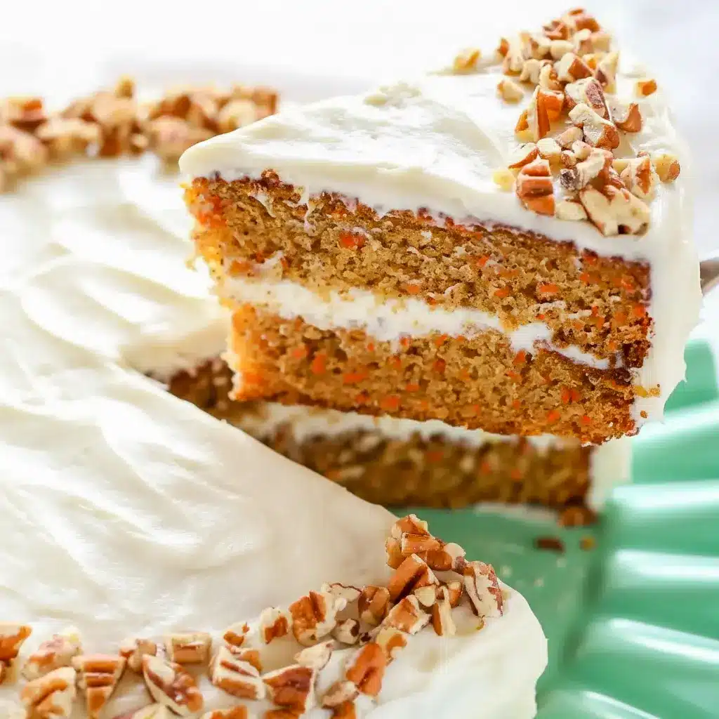 A beautifully layered Carrot Cake Recipe with fluffy Cream Cheese Frosting, featuring a thick slice that shows its tender crumb and rich texture. This Super Moist Carrot Cake is decorated with smooth frosting and simple carrot garnish, making it the perfect Easter Dessert or classic homemade cake for celebrations.